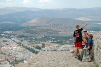 Eine Familie, die an einem Aussichtspunkt sitzt und auf Nafplion schaut