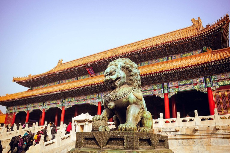 Peking Eine Löwen Statue vor einem typisch chinesichem Gebäude
